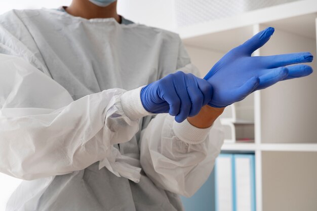 Side view doctor putting on protection gloves