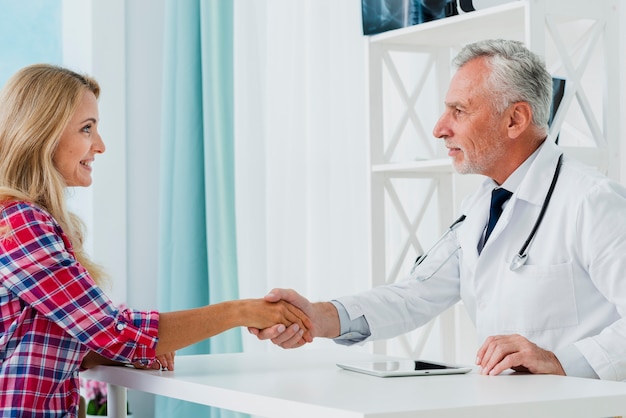 Side view doctor shaking patient hand