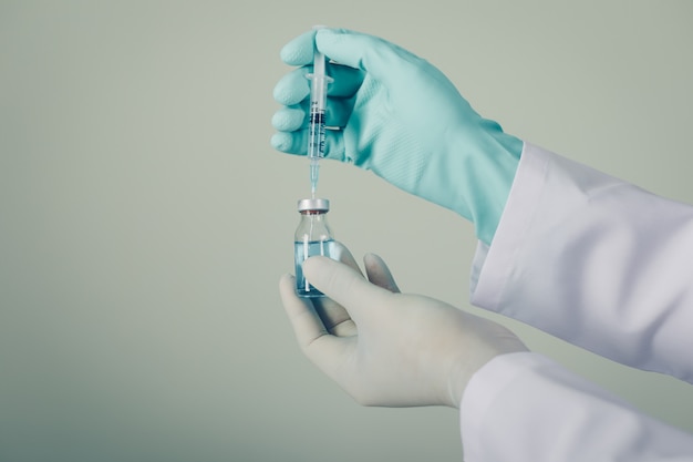 Side view doctor with gloves drawing medicine out of a vial. horizontal