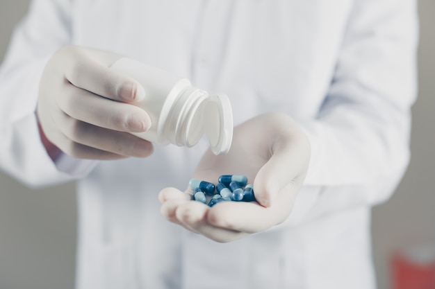 Side view doctor with gloves holding pills and bottle. horizontal