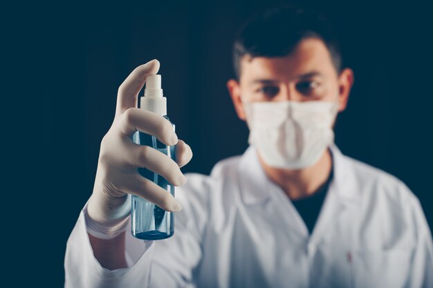 Side view doctor with mask holding medical spray in his hand