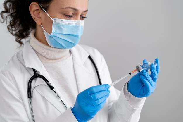 Side view doctor with mask holding syringe and vial