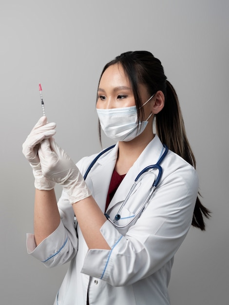 Free photo side view doctor with mask holding syringe