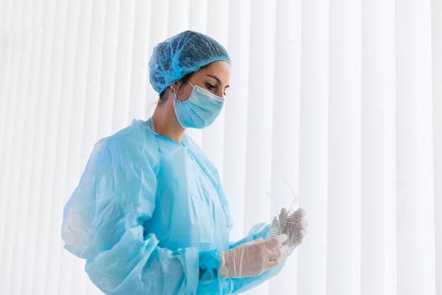 Side view doctor woman holding protective goggles