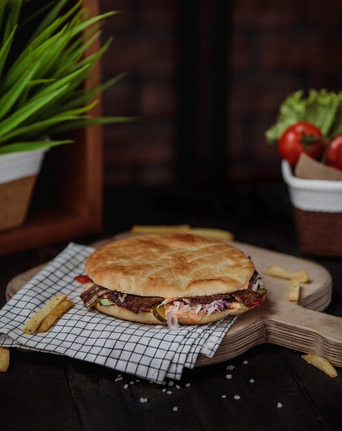 Free photo side view of doner kebab in pita bread on a wooden board