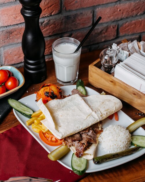 Side view of doner meat with french fries rice and vegetables on plate