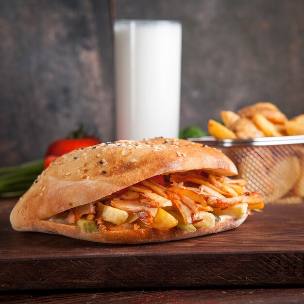 Side view doner with fried potatoes and ayran in board cookware