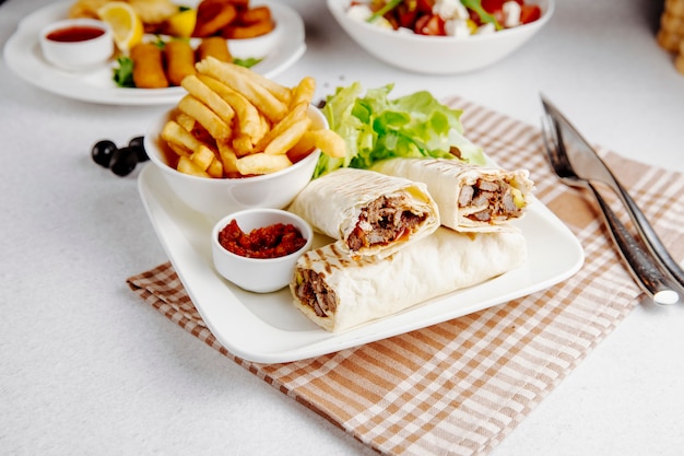 Side view of doner wrapped in lavash and fries on table