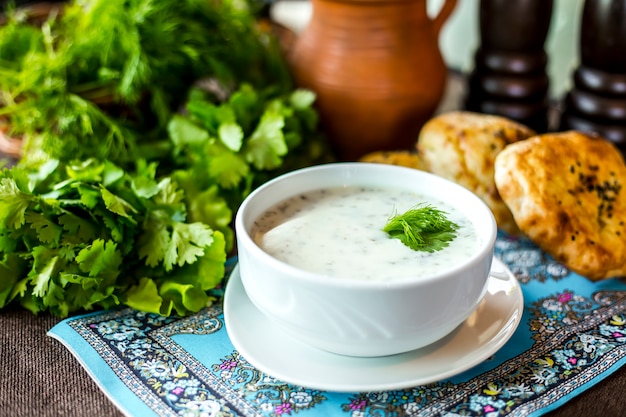 Side view dovga soup plain yogurt with herbs rice and bread on the table