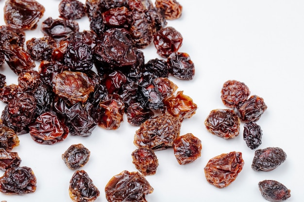 Side view of dried cherries scattered on white background