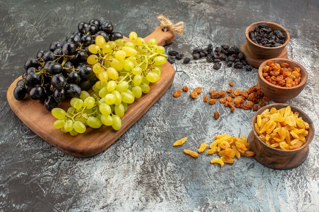 Side view dried fruits brown bowls of the appetizing colorful dried fruits grapes on the board