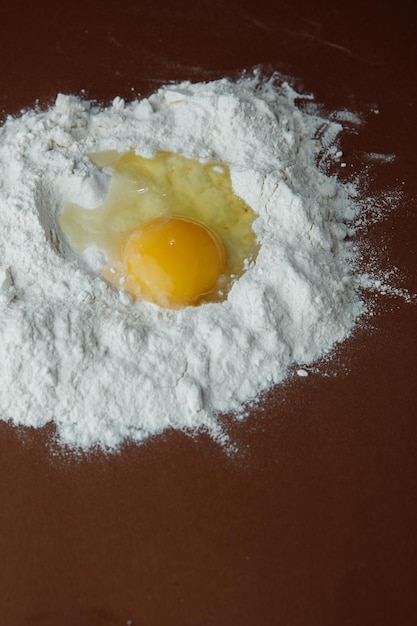 Side view of egg yolk on flour on brown background