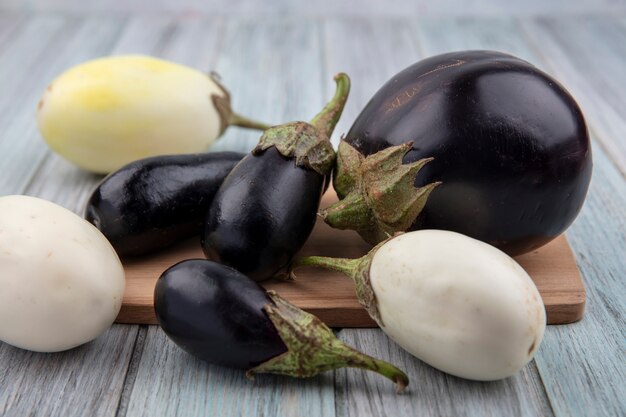 Side view of eggplants on cutting board and on wooden background