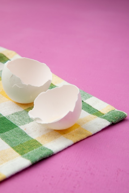 Free photo side view of eggshell on cloth surface and purple background with copy space