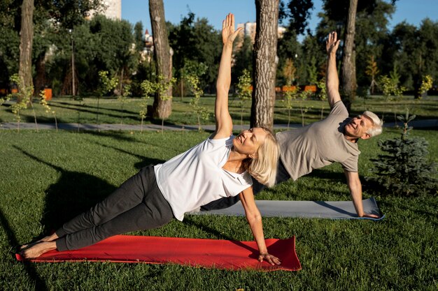 Side view of elder couple doing yoga outdoors