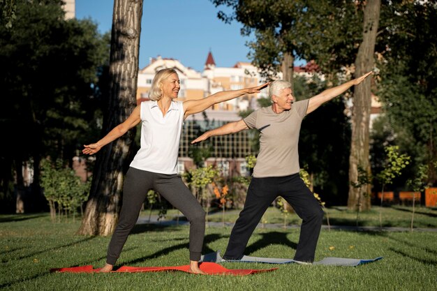 Side view of elder couple doing yoga outside