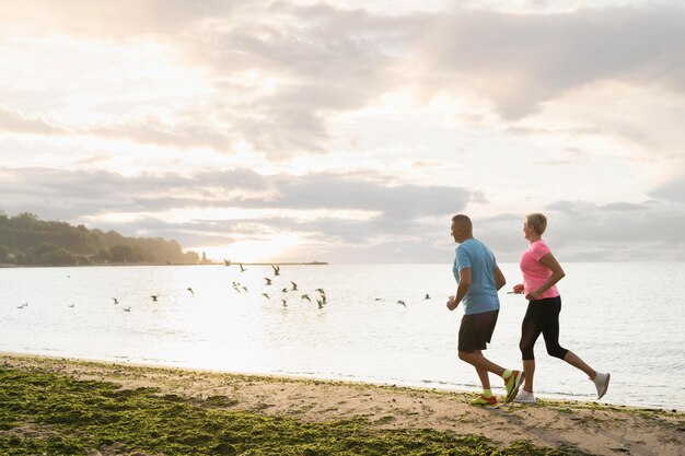 Side view of elder couple jogging on the beach