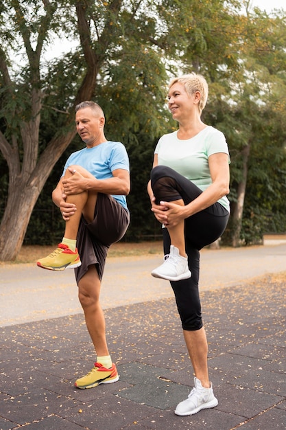 Free photo side view of elder couple warming up before exercising outdoors