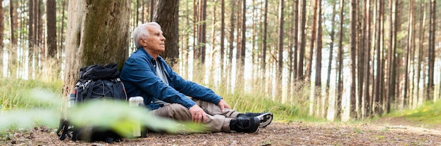 Free photo side view of elder man resting while backpacking and enjoying nature