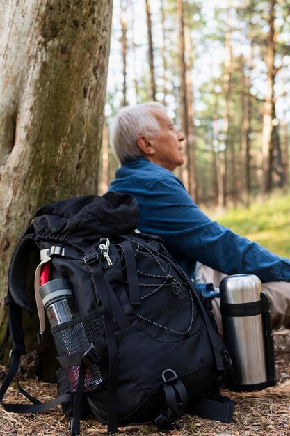 Side view of elder man resting while backpacking in nature