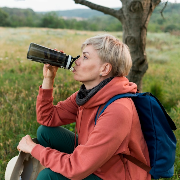 Vista laterale dell'acqua potabile della donna turistica più anziana