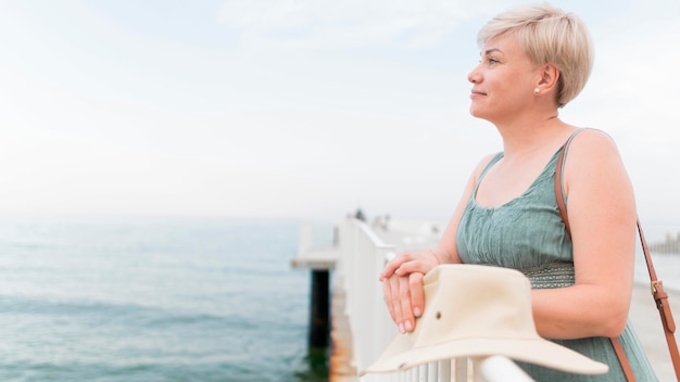 Free photo side view of elder tourist woman posing while at the beach