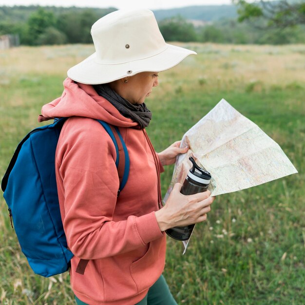 Side view of elder tourist woman with thermos and map