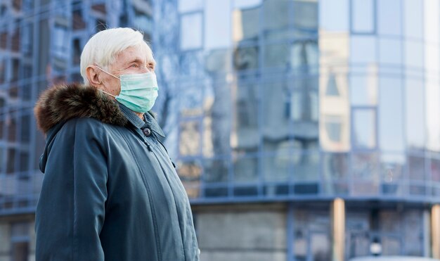 市内の医療用マスクを持つ高齢者の女性の側面図