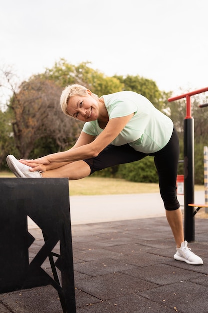 Free photo side view of elder woman working out outside in the park