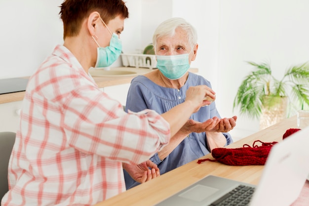 Side view of elder women at home sanitizing their hands