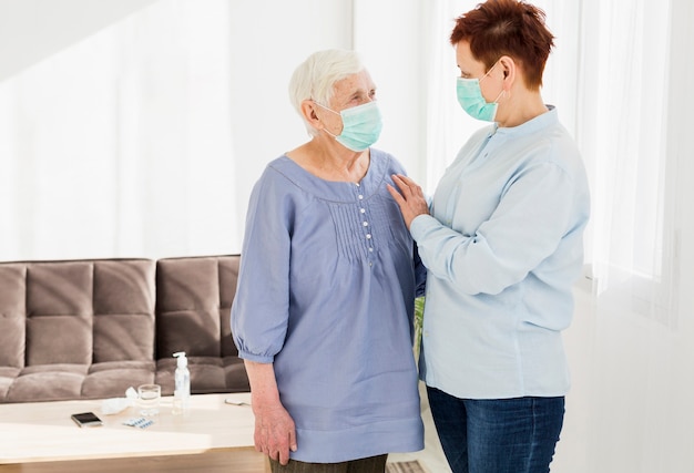 Free photo side view of elder women at home wearing medical masks