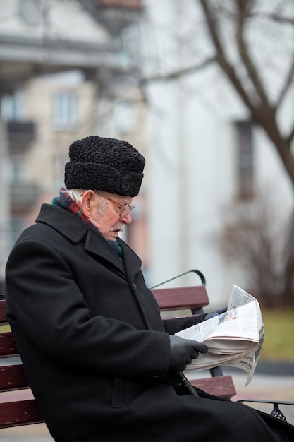 Side view elderly man reading newspaper