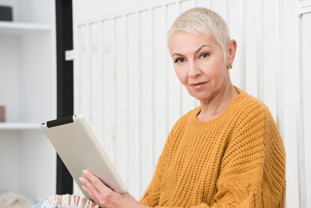 Side view of elderly woman holding tablet