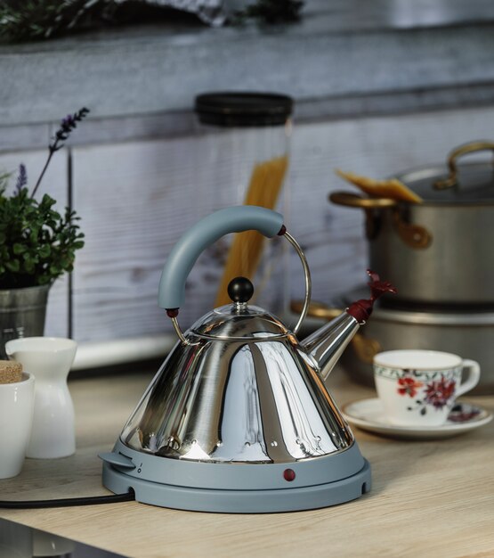 Side view of electric modern kettle with whistle on a wooden table in kitchen