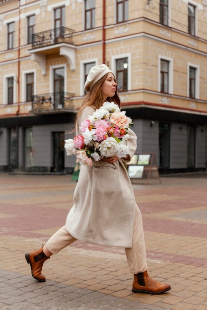 Side view of elegant woman outdoors holding bouquet of flowers in the spring