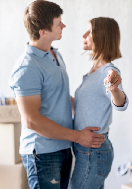 Side view of embraced couple holding the keys to new home