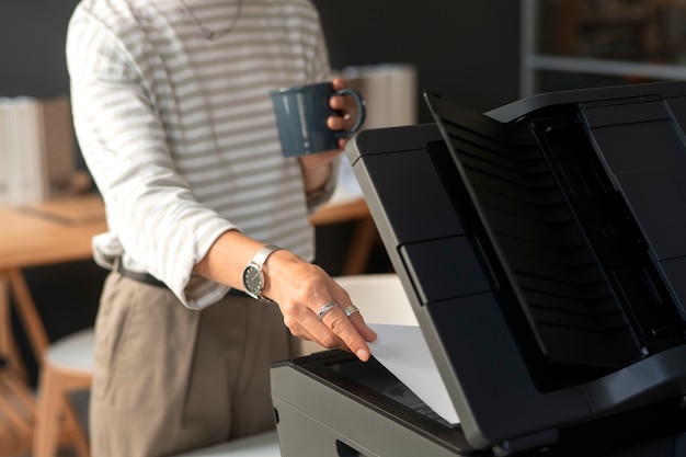 Бесплатное фото Боковой вид сотрудника, использующего принтер на работе