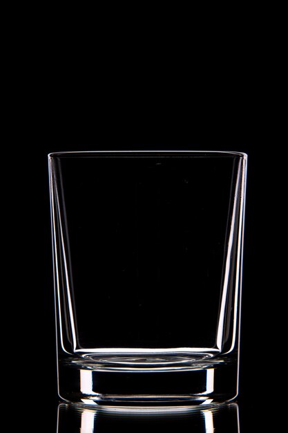 Side view of empty glass cup on dark wall with free space