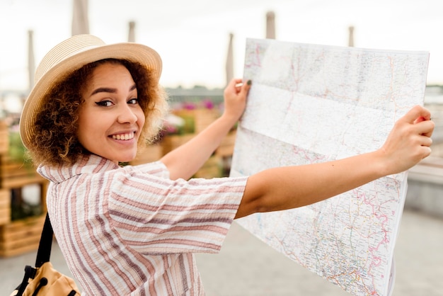 Donna entusiasta di vista laterale che viaggia da sola con una mappa