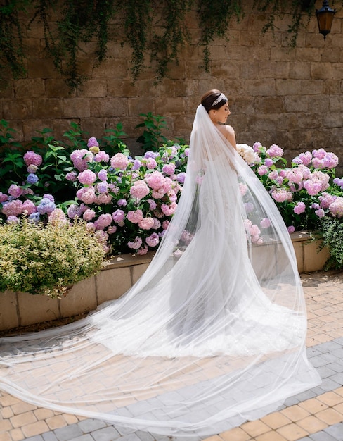 Side view of faceless female model dressed in stunning mermaid gown covered in embroidered floral lace with amazing