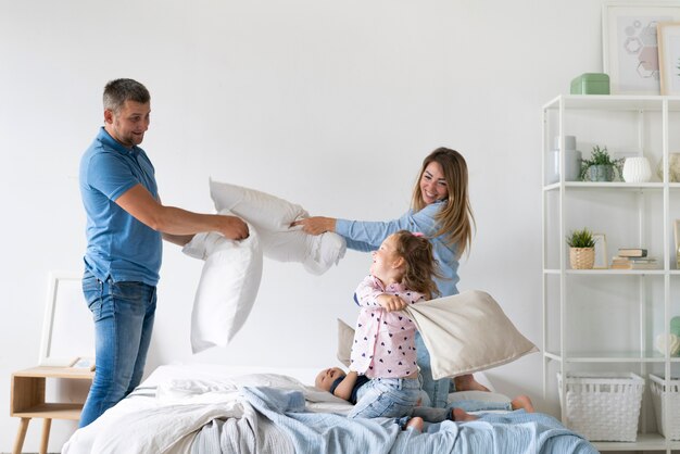 Side view family members fighting with pillows