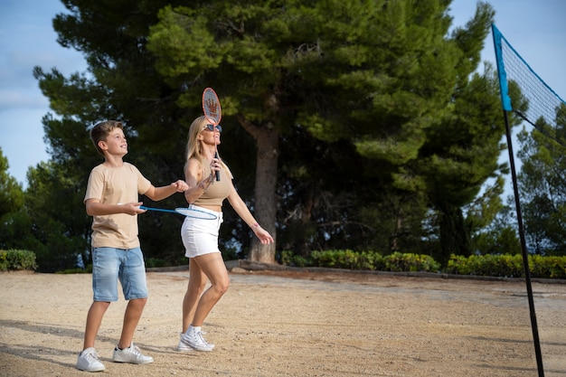 Side view family playing badminton