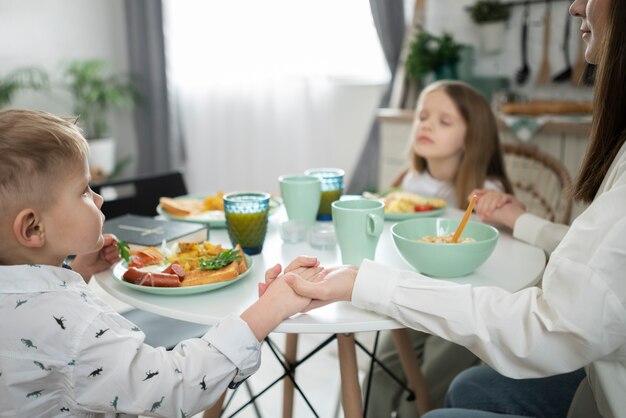 Side view family praying before eating