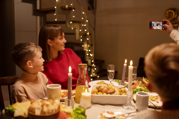 Free photo side view family taking selfie at table