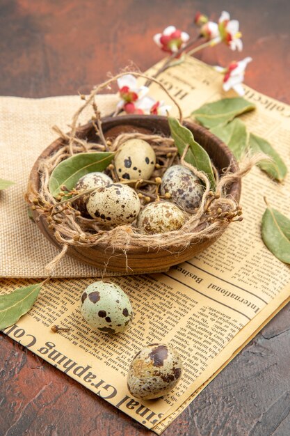 Side view of farm fresh eggs in a wooden pot and in a glass on an old newspaper on a brown background