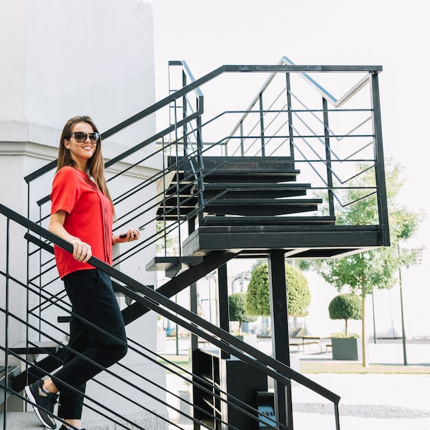 Vista laterale di una donna alla moda che si muove giù per le scale