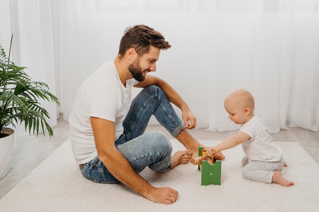 Vista laterale del padre e del bambino che giocano insieme a casa