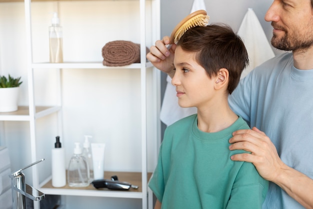 Free photo side view father brushing kid