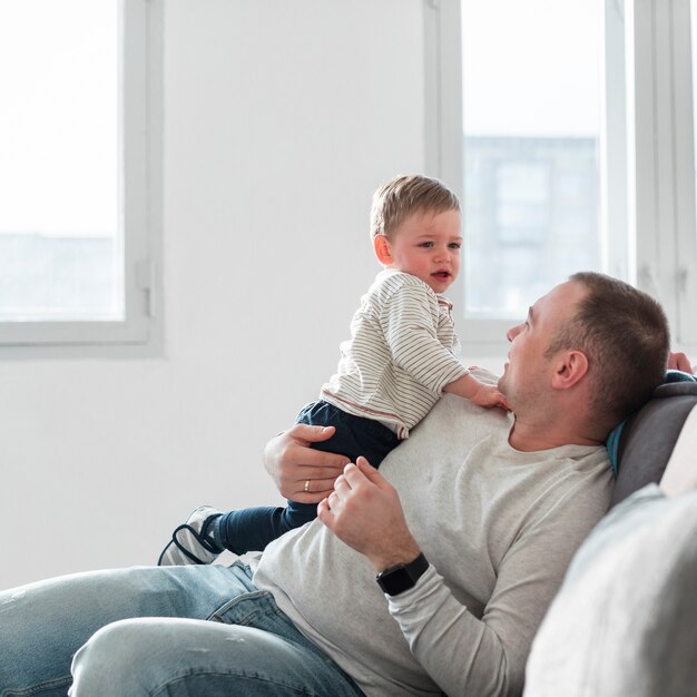 Вид сбоку отца на диване с ребенком
