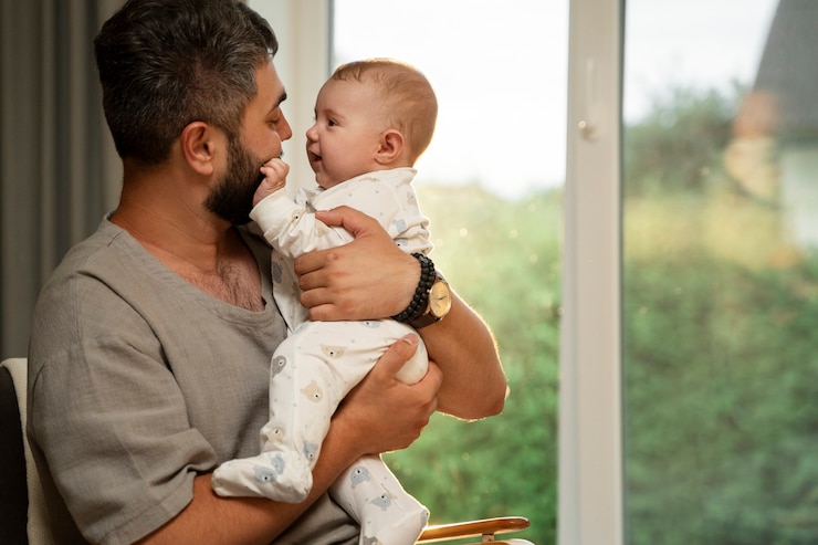 Free Photo side view father holding baby at home